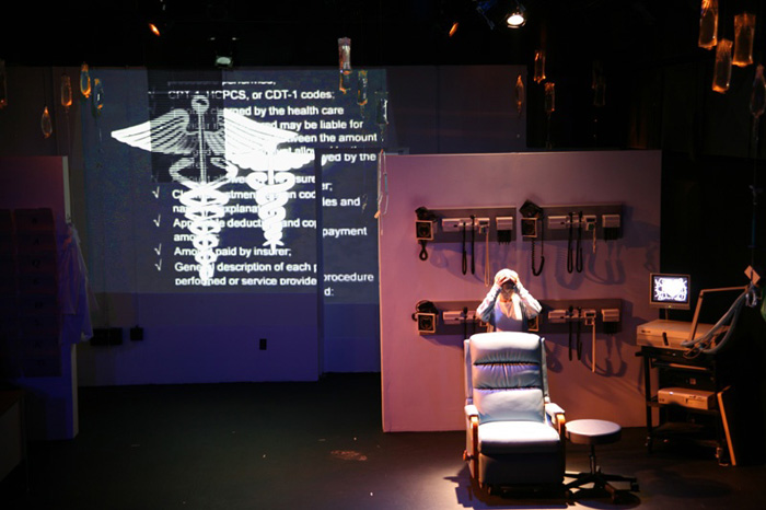 Paul Clay's Set Design, Lighting Design, and Video Design, for the production entitled Not God, Health Admin Nightmares.